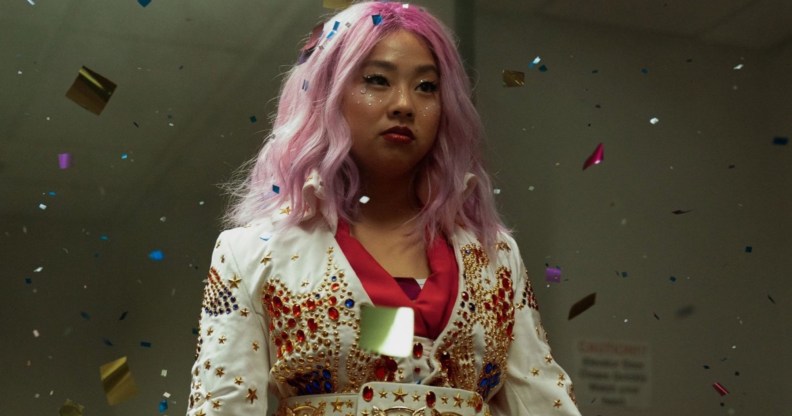 A screenshot from the movie Everything Everywhere All at Once shows actor Stephanie Hsu as character Joy who's dressed in a white and red oriental-style outfit with her hair dyed pink.