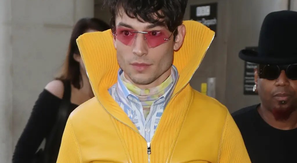 Ezra Miller in a yellow coat and sunglasses