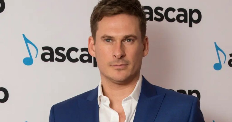 Lee Ryan in a blue suit with white open collar shirt