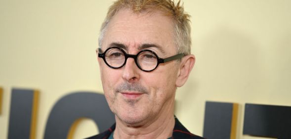 Alan Cumming in black glasses with blonde hair