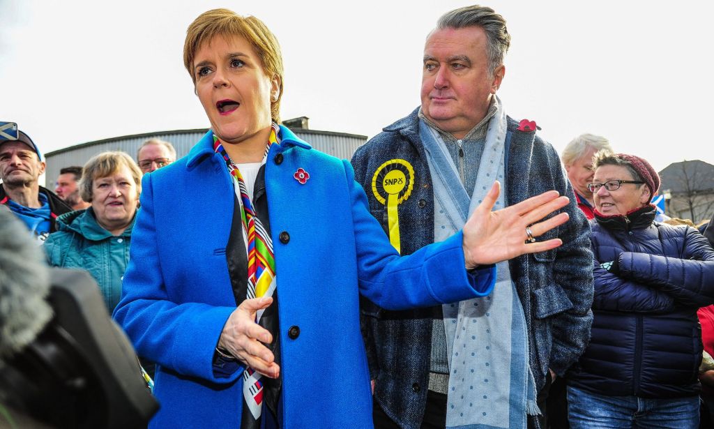 MSP John Nicolson and Nicola Sturgeon appear in front of a crowd wearing Scottish National Party (SNP) pins on their chests during a campaign run