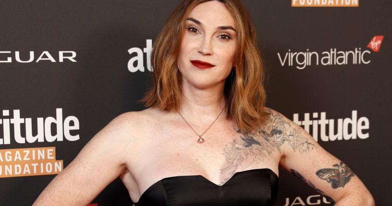 Trans author Juno Dawson wears a black dress with her hands on her hips