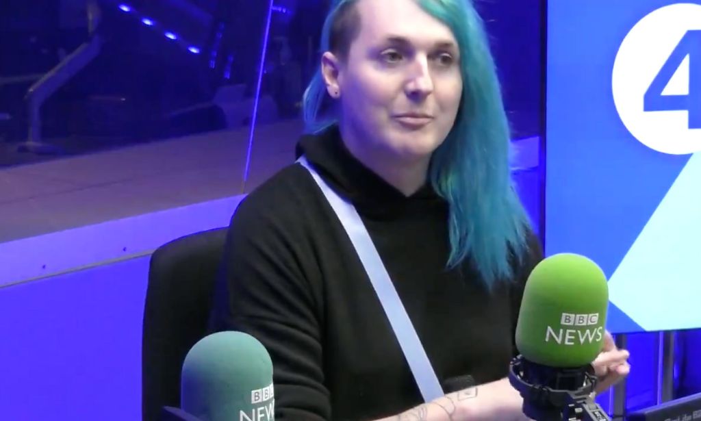 Laura Kate Dales wears a dark top and has blue long hair with an undercut while appearing during a BBC Radio interview discussing Gender Recognition Certificates