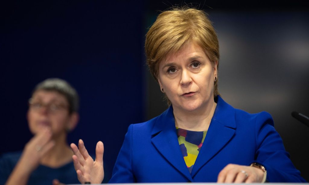 Scotland's first minister Nicola Sturgeon wears a blue jacket as she stands at a podium during a press conference