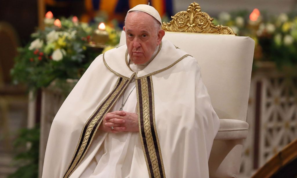 Pope Francis wears his white cassock while he sits on a white and gold chair during mass