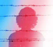 The silhouette of a women against prison wires in the colours of the trans Pride flag
