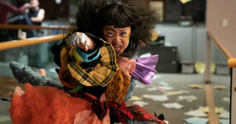 Stephanie Hsu as Joy throwing a punch, with her face painted in clown make-up