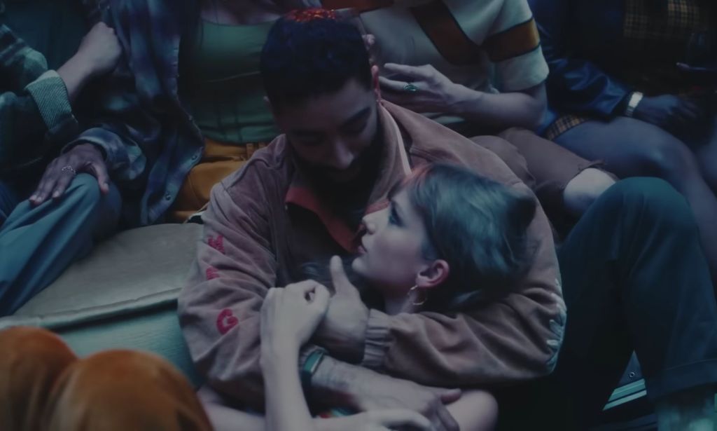 Taylor Swift is held in the arms of trans model Laith Ashley during a house party scene in her "Lavender Haze" music video