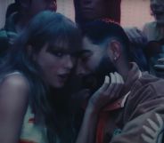 Taylor Swift looks towards the camera as she holds the face of Laith Ashley, a trans model and singer, in a house party scene in her "Lavender Haze" music video