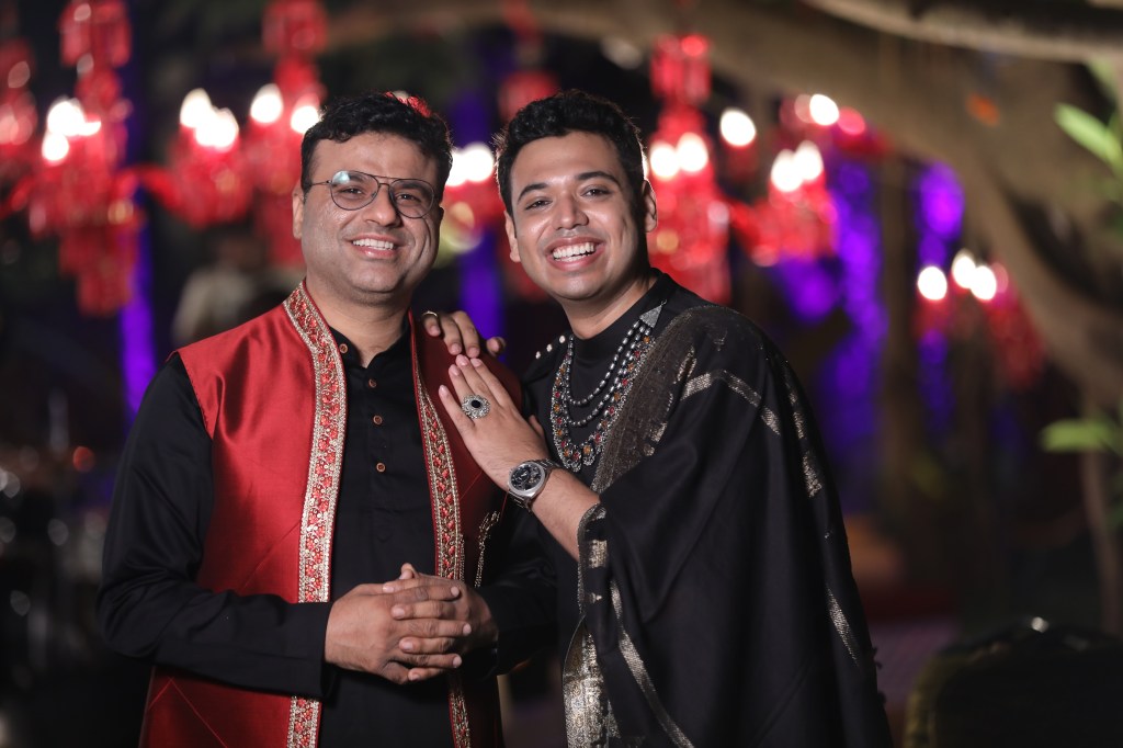 Abhay and Supriyo smiling in front of bright lights