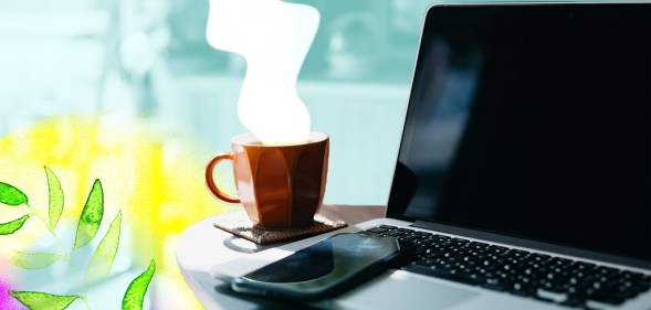 A steaming cup of coffee sits next to an open laptop and mobile phone.
