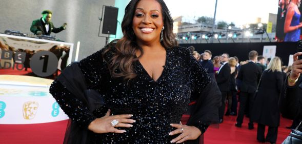 Alison Hammond with her hands on her waist as she smiles on the BAFTA red carpet