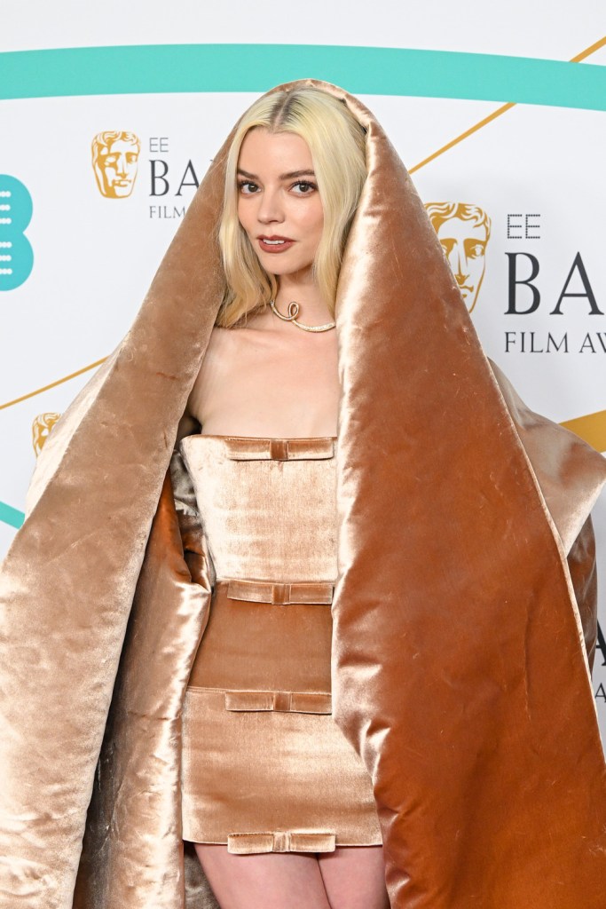 Anya Taylor-Joy at the BAFTA red carpet in a light brown hood, cape and mini-dress ensemble.