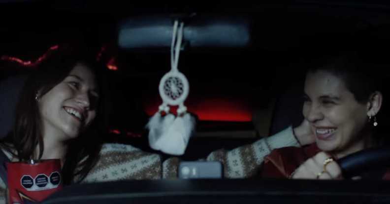 A screenshot from Doritos' 'Bold love' advert shows two women sitting next to each other in a car smiling with one woman touching the other's head.