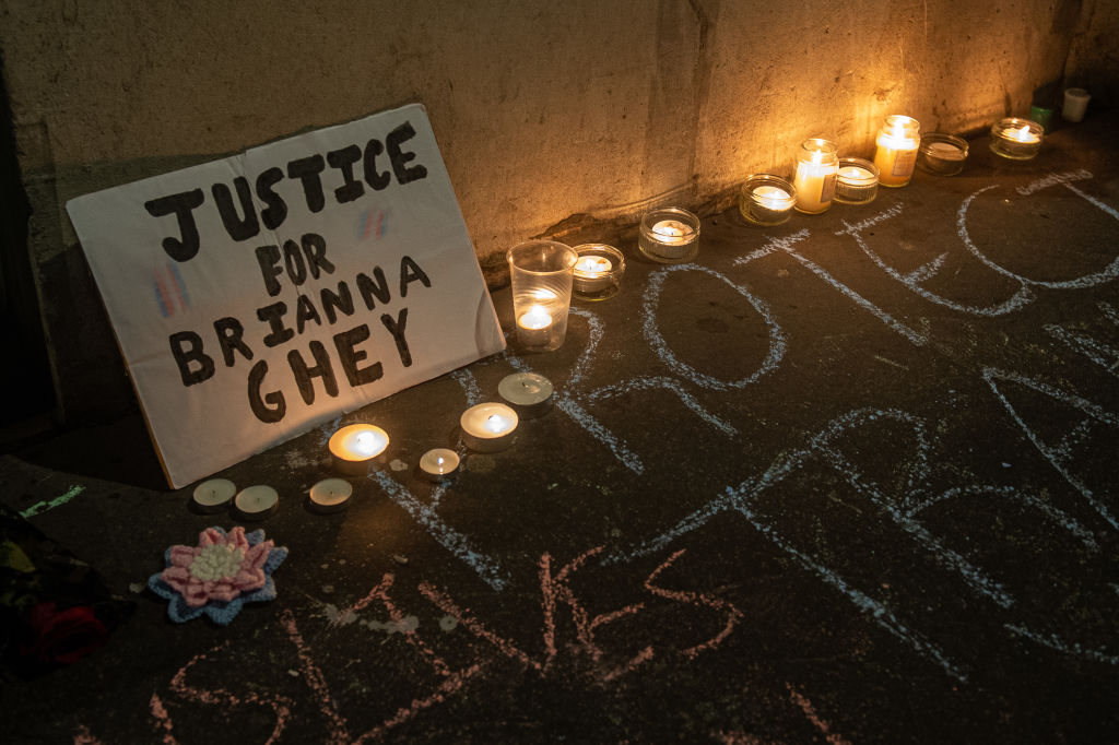 LGBTQ+ people hold a vigil for Brianna Ghey outside of the Department of Education in London. The picture shows a sign propped against the wall which reads "Justice for Brianna Ghey". It is surrounded by candles and a message about protecting trans lives is written in chalk on the pavement.