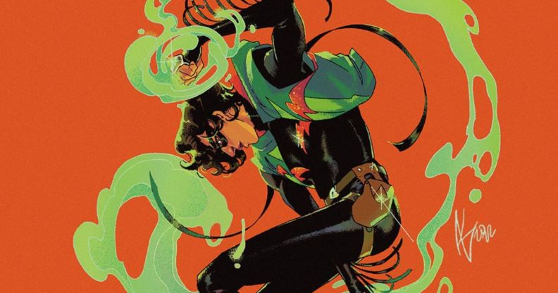 A promo image of new trans non-binary DC Comics superhero, Circuit Breaker. The image is set on an orange background with the character dressed in black wearing a black eyemask and is looking down as his arms are drawn in a way that suggests they're moving in a spiral fashion and there's a green mist that can be seen around him