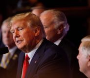 A photo shows Donald Trump wearing a navy suit, whit shirt and red tie speaking to an audience during a campaign speech.