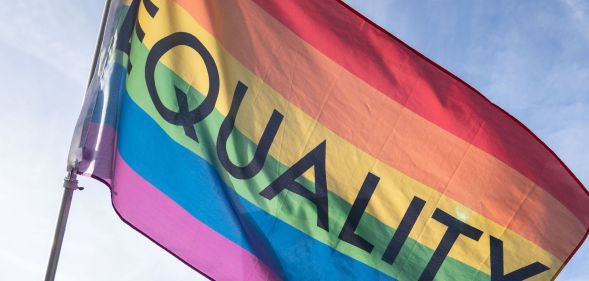 A rainbow flag with the word "equality" flying in the air.