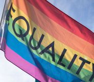 A rainbow flag with the word "equality" flying in the air.