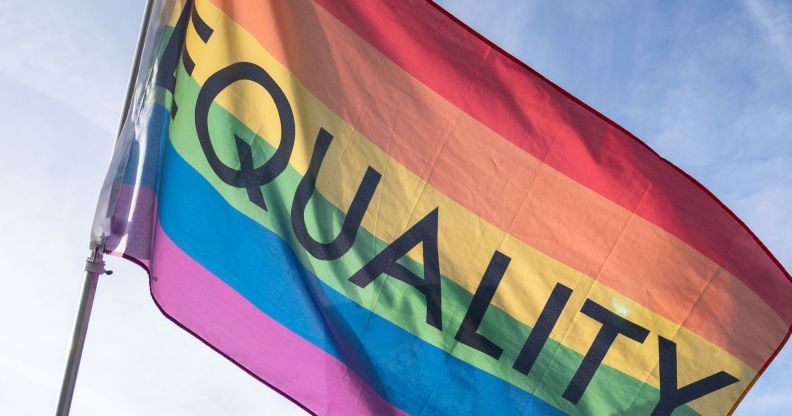 A rainbow flag with the word "equality" flying in the air.