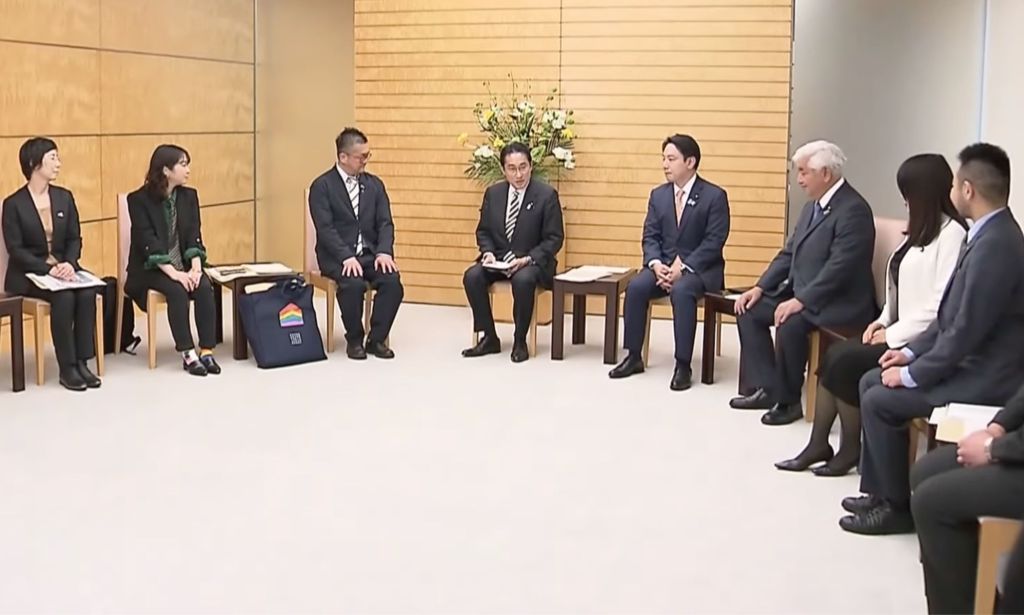 Japanese prime minister Fumio Kishida sits in the centre of a group of people as he meets with LGBTQ+ activists
