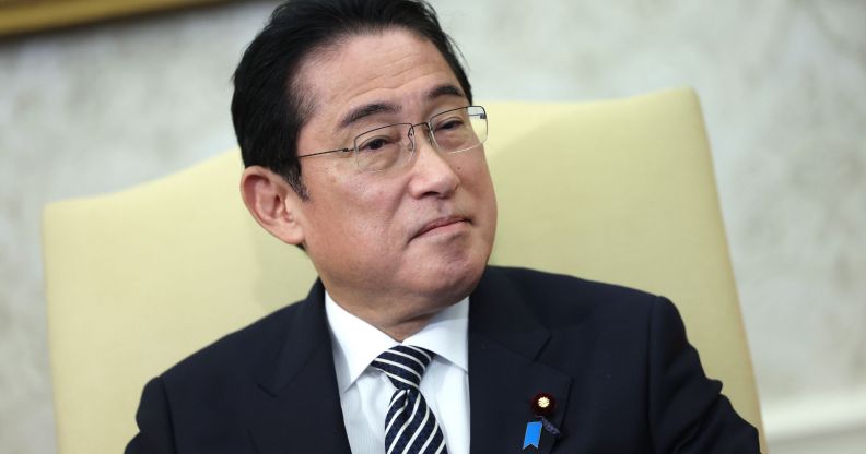 Japan’s prime minister Fumio Kishida wears a white shirt, dark striped tie and dark suit jacket as he sits in a cream-coloured chair during a meeting