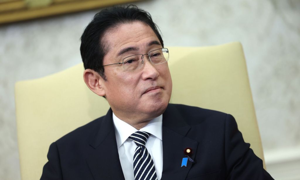 Japan’s prime minister Fumio Kishida wears a white shirt, dark striped tie and dark suit jacket as he sits in a cream-coloured chair during a meeting