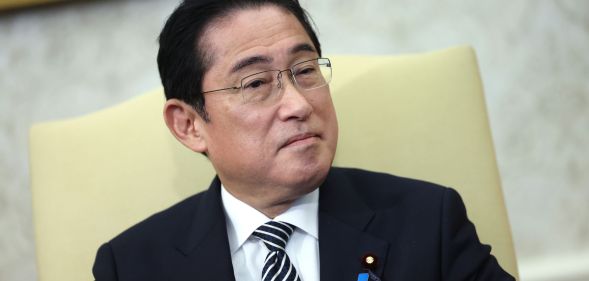Japan’s prime minister Fumio Kishida wears a white shirt, dark striped tie and dark suit jacket as he sits in a cream-coloured chair during a meeting