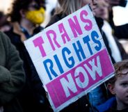 Pro-trans activists hold up a 'Trans Rights Now' placard.