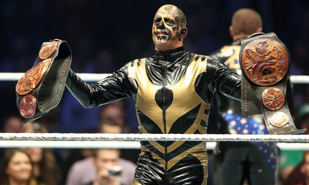 Goldust holding the WWE tag team championship belts after a win.