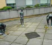 A photo shows the Gorbals Boys artwork piece in Glasgow. There are three statues showing three boys in different positions wearing women's shoes