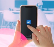 A phone is being held up with the LinkedIn icon in the center.