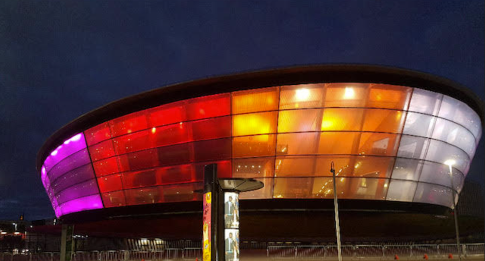 A photo showing the OVO Hydro Arena in Glasgow illuminated in lesbian Pride flag colours