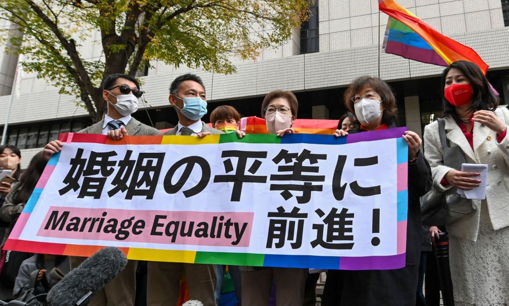 LGBTQ+ activists hold up a sign in protest of Japan's ban on marriage equality.