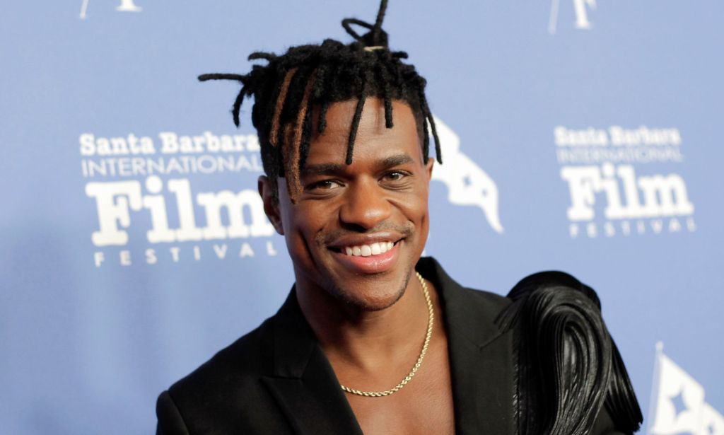Jeremy Pop wears a black blazer and gold chain while smiling on the red carpet at the 38th Annual Santa Barbara International Film Festival.