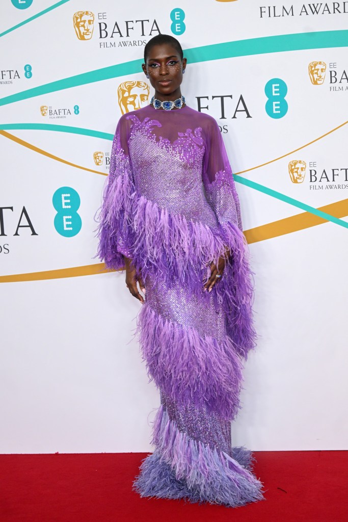 Jodie Turner-Smith wears a purple, feathery gown at the BAFTA 2023 red carpet.