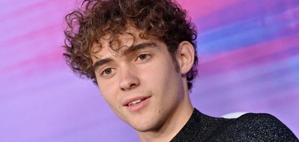 Joshua Bassett in front of a blue, pink and purple background.