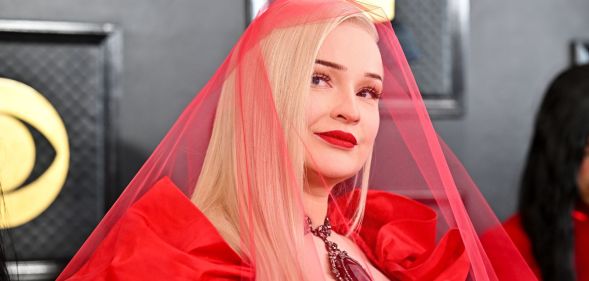 Kim Petras wears a sheer red veil on the red carpet at the 2023 Grammy awards.