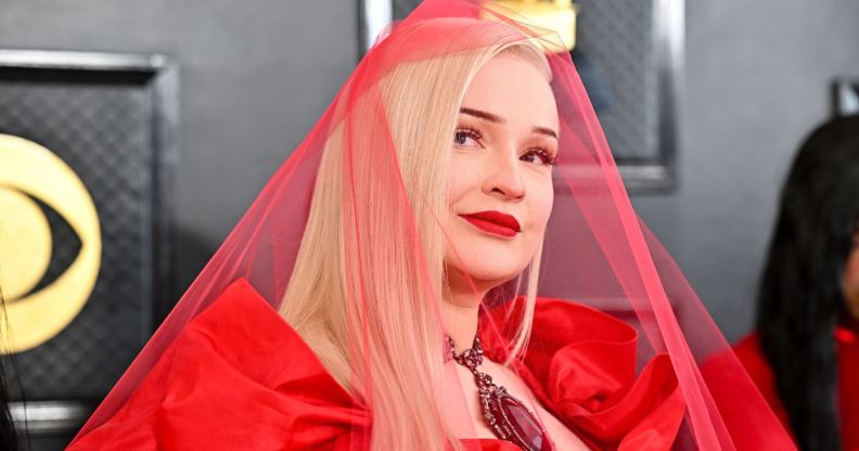 Kim Petras wears a sheer red veil on the red carpet at the 2023 Grammy awards.