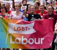 A photo showing LGBT+ Labour at Pride marching amongst a large crowd as they hold a banner that says "LGBT+ Labour"