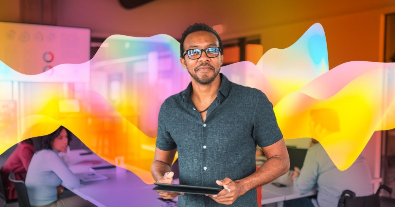 A man is holding a tablet and looking directly at the camera.