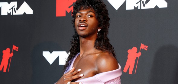 Lil Nas X wears a long black wig and off-the-shoulder lilac dress at the MTV VMAs 2021