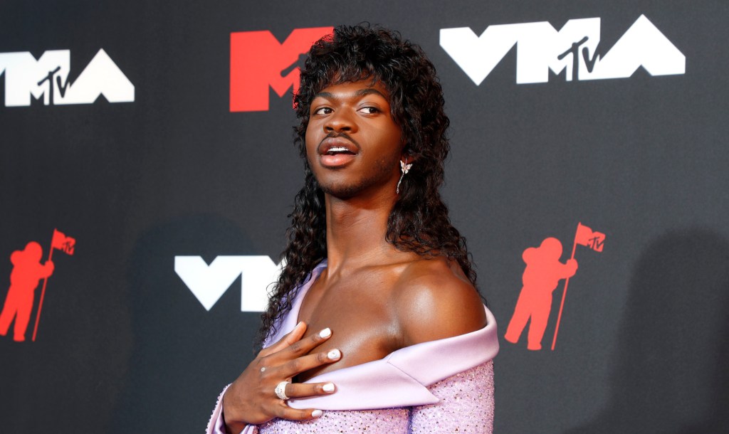 Lil Nas X wears a long black wig and off-the-shoulder lilac dress at the MTV VMAs 2021