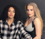 A photo of MTV's Love At First Lie winners Stephanie wearing a black and white-check shirt and Arabella who is wearing a grey bra vest top as they stand against a grey background. (Provided)