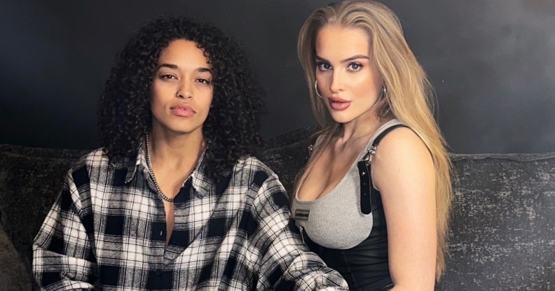 A photo of MTV's Love At First Lie winners Stephanie wearing a black and white-check shirt and Arabella who is wearing a grey bra vest top as they stand against a grey background. (Provided)