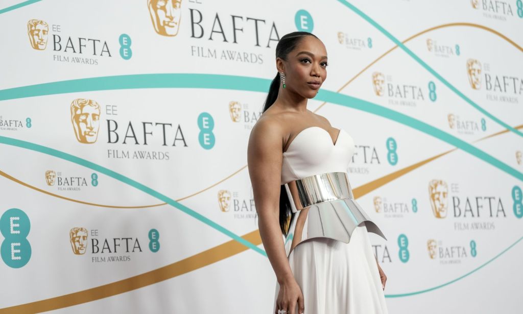 Naomi Ackie in a white gown and silver mid-piece at the BAFTA red carpet.