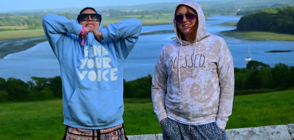 Photo of two people wearing hoodies standing in a rural setting, with a river behind them, at Old & Wild Festival