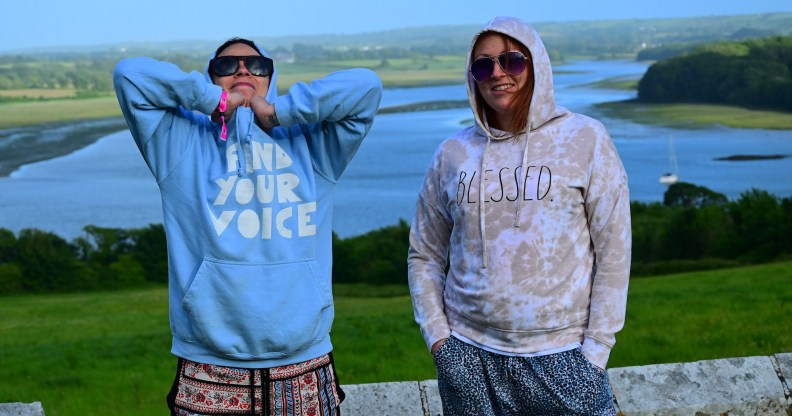 Photo of two people wearing hoodies standing in a rural setting, with a river behind them, at Old & Wild Festival