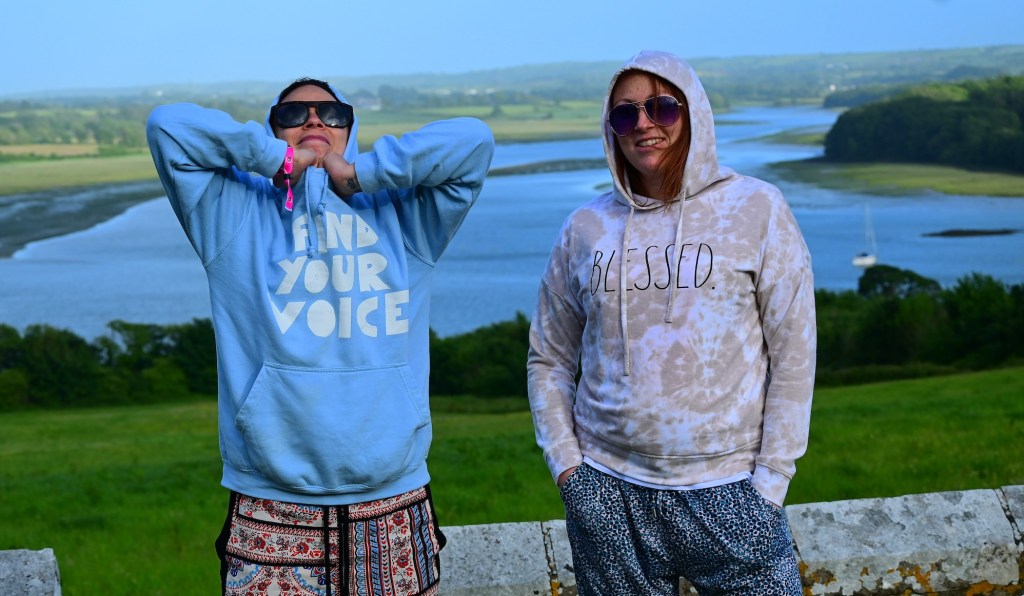 Photo of two people wearing hoodies standing in a rural setting, with a river behind them, at Old & Wild Festival