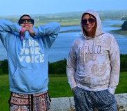 Photo of two people wearing hoodies standing in a rural setting, with a river behind them, at Old & Wild Festival